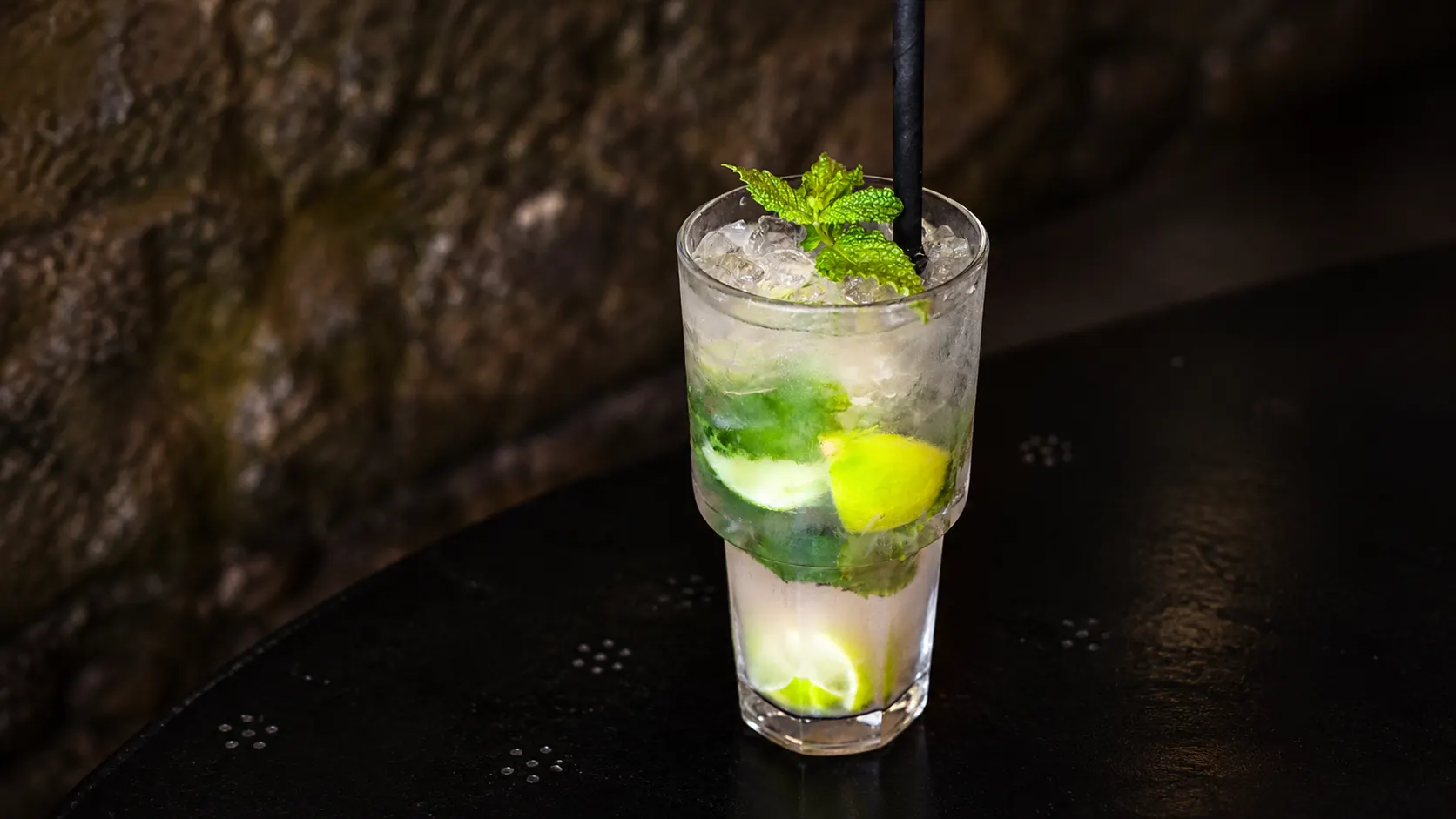 A mojito in a tall glass, with crushed ice, lime and a sprig of mint.